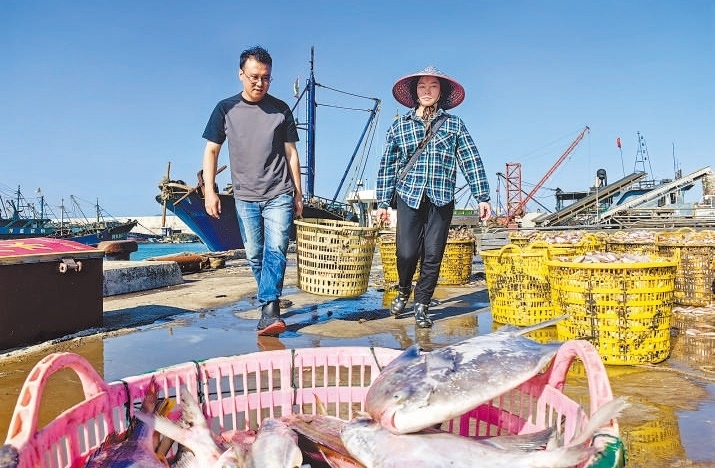 許小斌（左）和漁民一起搬運海鮮。本報記者 付 文攝