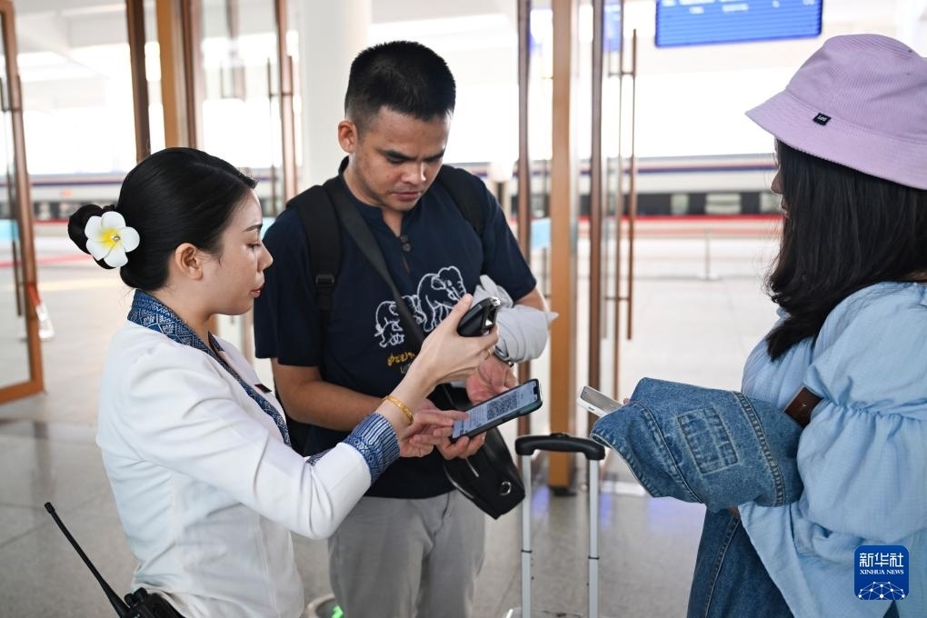 10月12日，在老撾萬象中老鐵路萬象站，工作人員檢驗(yàn)乘客車票。新華社記者 程一恒 攝