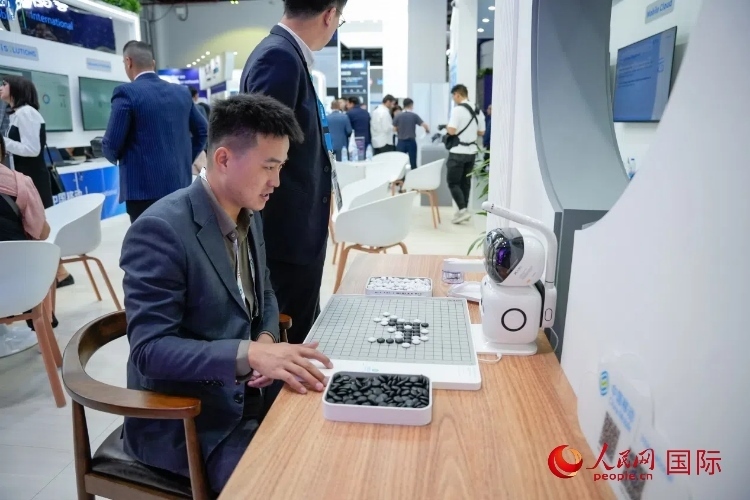觀眾在中國移動國際有限公司展臺體驗智慧圍棋機器人。人民網(wǎng) 塔里克·易卜拉欣攝