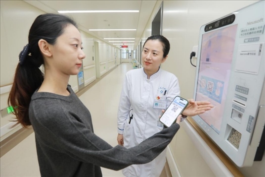 醫(yī)護人員引導患者在自助機前辦理自助入院手續(xù)。圖片來源：山東第一醫(yī)科大學第二附屬醫(yī)院