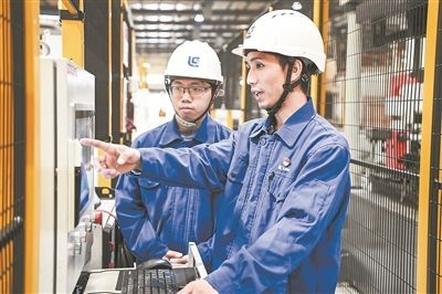 在廣西柳工機(jī)械股份有限公司生產(chǎn)車間內(nèi)，一名高級(jí)技師（右）給徒弟講解數(shù)控設(shè)備操作細(xì)節(jié)。新華社記者 曹祎銘攝