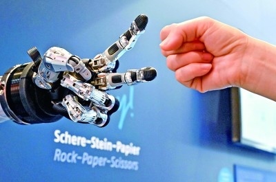 在德國漢諾威工博會上，參觀者與一款智能機(jī)器人進(jìn)行“石頭剪子布”游戲。新華社發(fā)