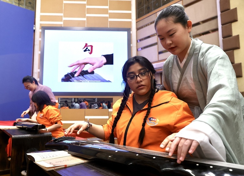 2024年3月20日，美國(guó)華盛頓州中學(xué)生代表團(tuán)北京大學(xué)交流活動(dòng)在北京大學(xué)英杰交流中心舉行。圖為來自華盛頓州的中學(xué)生體驗(yàn)古琴。