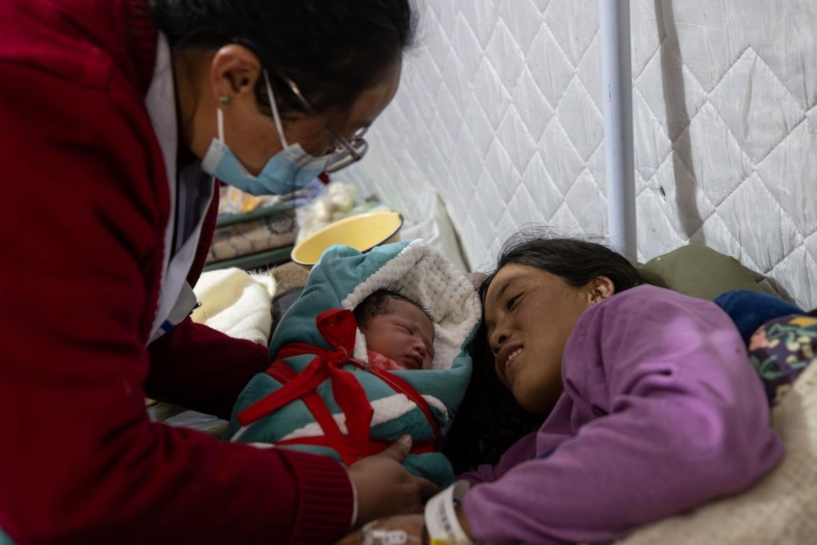 1月10日，定日縣中心醫(yī)院的婦產(chǎn)科醫(yī)生悉心照看一位母親和她懷里的新生兒。人民日報記者張武軍攝