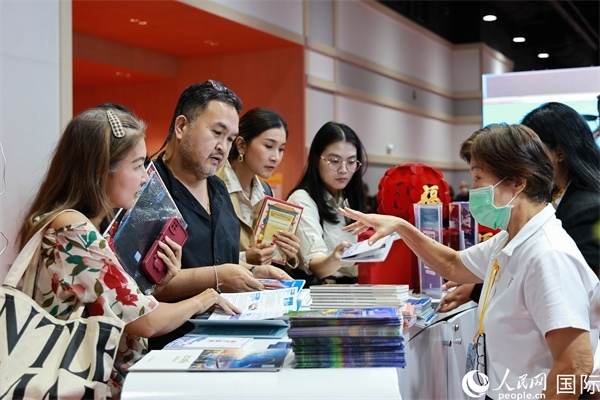 外國觀眾在中國展臺(tái)仔細(xì)閱讀赴華旅游介紹，向工作人員咨詢關(guān)于中國美食和景點(diǎn)的詳細(xì)信息。人民網(wǎng)記者 白元琪攝