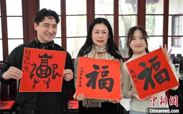 1月20日，外籍留學(xué)生和西泠印社社員李硯(中)展示各自創(chuàng)作的福貼。當(dāng)日，來自巴西、馬來西亞、加納、哈薩克斯坦的外籍留學(xué)生在浙江杭州西泠印社體驗福貼、春聯(lián)和篆刻，感受古老的中國傳統(tǒng)文化。中新社記者 王剛 攝