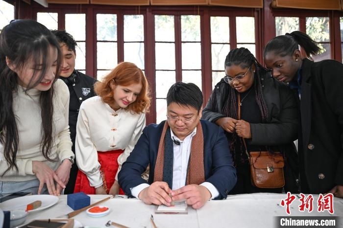 1月20日，篆刻家王臻向外籍留學(xué)生展示篆刻印章。當(dāng)日，來自巴西、馬來西亞、加納、哈薩克斯坦的外籍留學(xué)生在浙江杭州西泠印社體驗福貼、春聯(lián)和篆刻，感受古老的中國傳統(tǒng)文化。中新社記者 王剛 攝