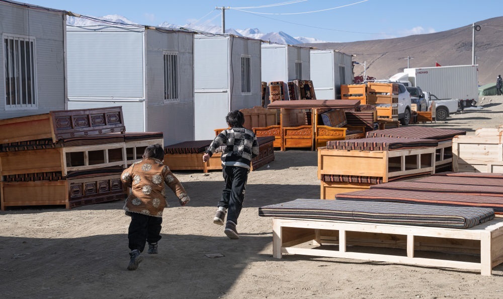 2025年1月13日，在定日縣嘎旦村，兩個孩子在剛運來的兩排藏床間奔跑。新華社記者丁增尼達 攝