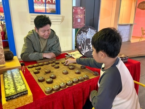 柯秋楓與市民下椰雕象棋。人民網(wǎng) 陳葉欣攝