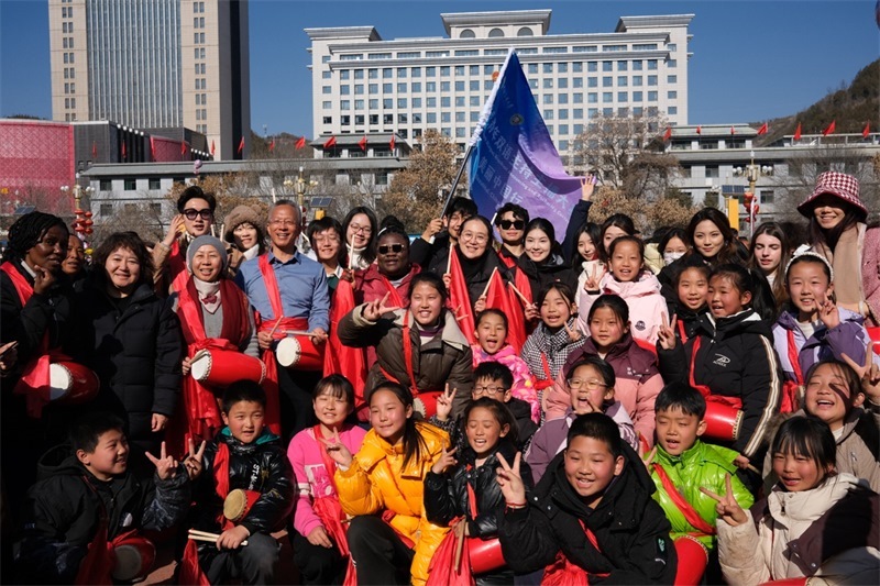 中外青年學(xué)子在安塞文化廣場(chǎng)觀看陜北腰鼓和大秧歌表演后合影留念，大家踏著鼓點(diǎn)共舞，翻飛的紅綢與躍動(dòng)的身影交織，在黃土地廣場(chǎng)上繪出一幅生動(dòng)的陜北民俗互動(dòng)畫卷