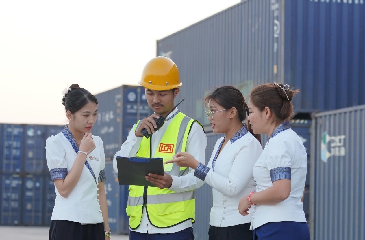 萬象南站貨運值班員陳尼啦（左一）與同事在一起討論工作。老中鐵路有限公司供圖