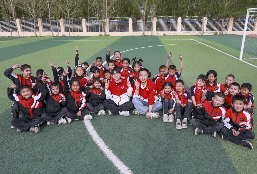 4月23日，在新疆克州阿圖什市哈拉峻鄉(xiāng)謝依特小學(xué)，支教教師王俊文（中左）、李軻凡（中右）和學(xué)生在一起。