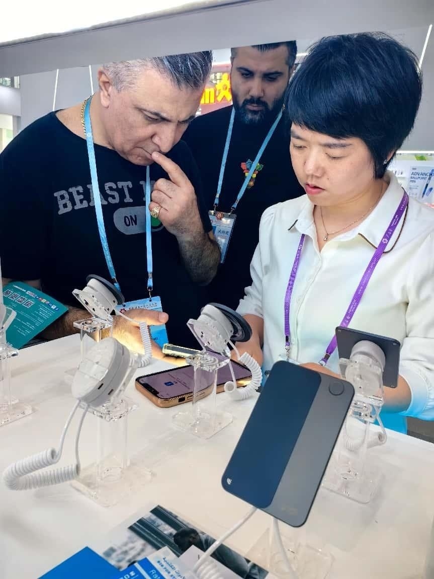 展臺(tái)工作人員向外商展示“AI TOP翻譯終端”。圖片來(lái)源：受訪(fǎng)者提供