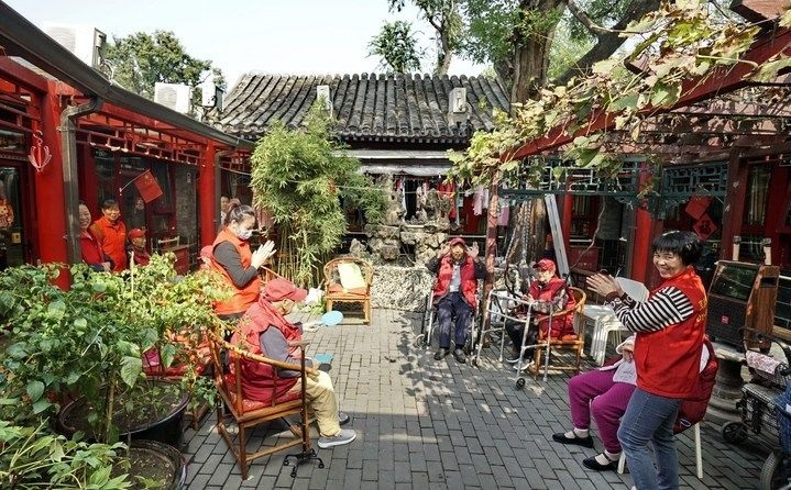 2024年10月12日，鐘樓灣胡同的老年人在社區(qū)內(nèi)的四合院養(yǎng)老驛站休閑。2017年起，北京市先后開(kāi)展了兩輪背街小巷環(huán)境整治提升行動(dòng)，完整保留了中軸線生活建筑群的歷史信息，并根據(jù)居民的生活和居住方式進(jìn)行適配化的更新和改造，極大地改善了生活環(huán)境。2023年鐘樓灣胡同被評(píng)為“北京最美街巷”。