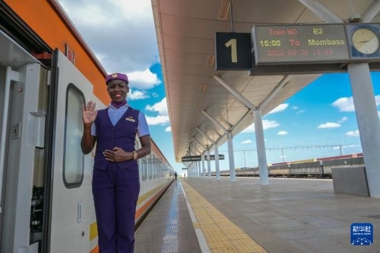 5月31日，在蒙內(nèi)鐵路內(nèi)羅畢站，一名乘務(wù)員在即將開往蒙巴薩的E2次列車旁等候乘客。新華社記者 楊光 攝