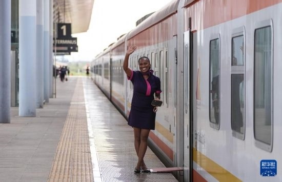 5月31日，在蒙內(nèi)鐵路內(nèi)羅畢站，一名乘務(wù)員在即將開往蒙巴薩的E2次列車旁等候乘客。新華社記者 李亞輝 攝
